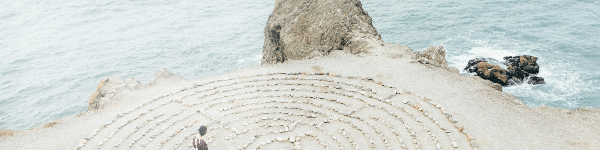 Woman walks through stone labyrinth on the beach 