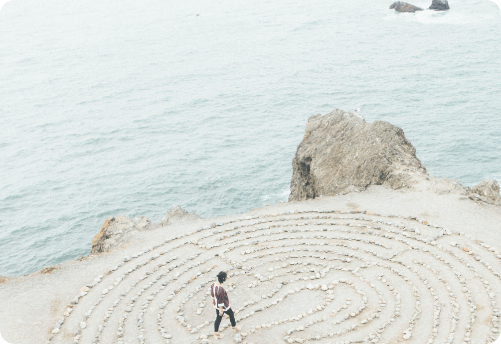 Woman walks through stone labyrinth on the beach 